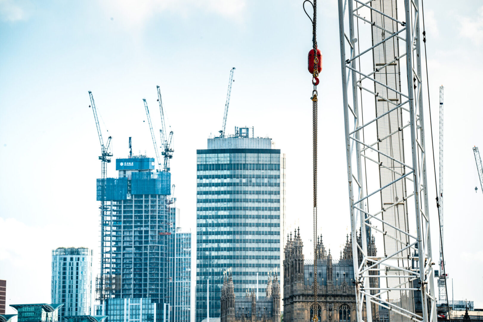 City skyline with cranes and modern buildings.